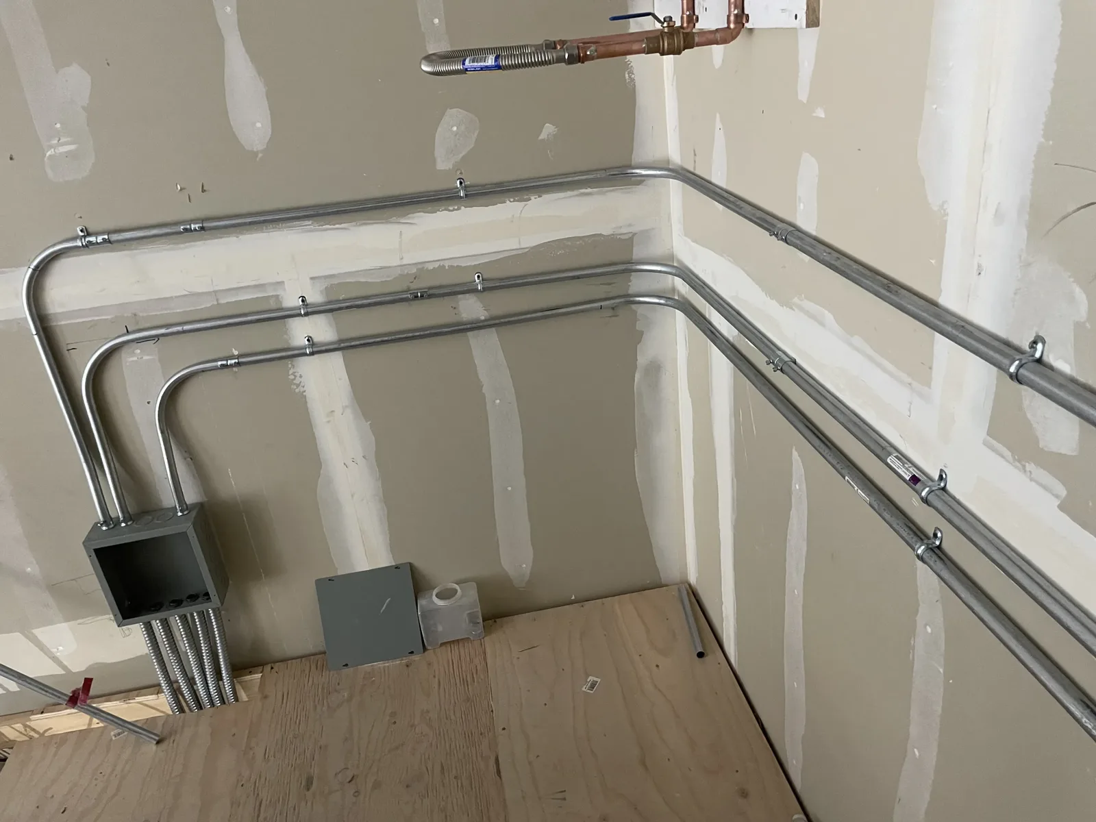 Neatly bent conduit runs and a junction box installed before wall finishes