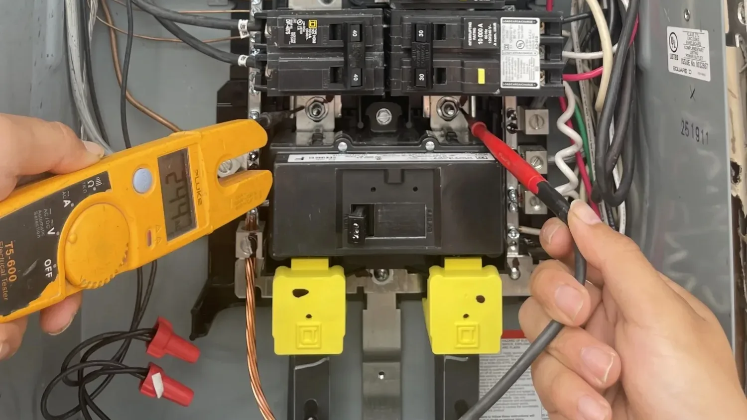 Electrician measuring voltage at a panel's main lugs with a Fluke tester